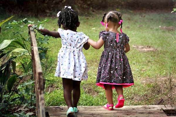 Two little girls walking hand in hand in a field